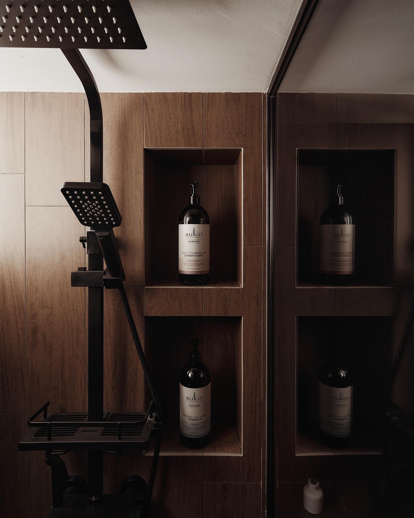 Wood-look shower with black fittings and recessed shelves