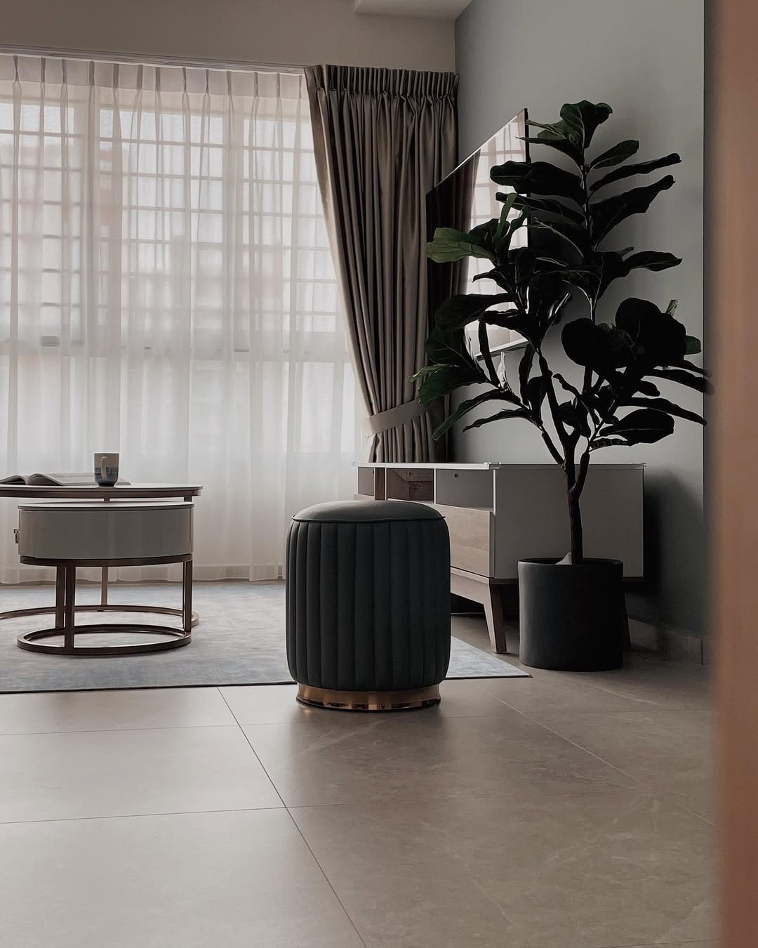 Calm living room with sheer curtains, velvet ottoman and fiddle-leaf fig